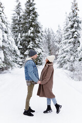 Man and woman looking at each other in winter forest.