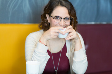 bella ragazza  chiara con gli occhiali prende un tea in un bar 