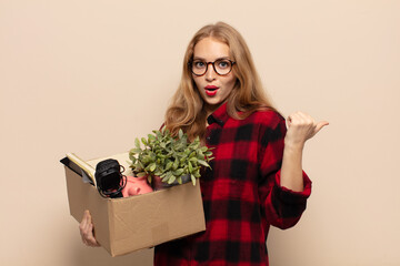 blonde woman looking astonished in disbelief, pointing at object on the side and saying wow,...