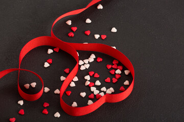 Valentines day concept with red hearts and red ribbon on black background, top view