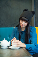 ragazza mora con cuffietta simpatica e un caldo maglione  si rilassa mentre prende una tisana calda in un bar 