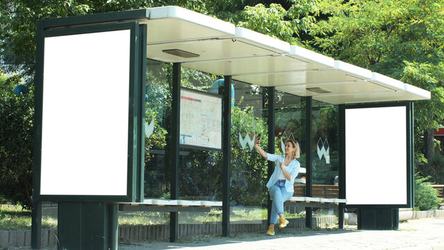 A bus stop in Istanbul.Vertical advertising billboard ad in the bus stop. White box for placement in advertising banners. A woman is taking selfie.