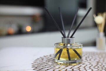 luxury aromatic scent of reed diffuser glass bottle is used as room freshener on the marble table in the bedroom with background of the light from the window and white bed in the morning
