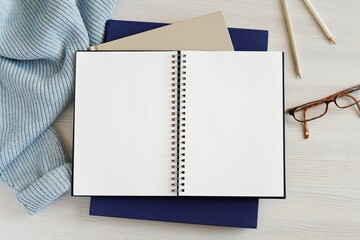 Open empty spiral notebook, planner mockup, space for text, blue sweater, glasses, diary, blog post template, flat lay on work desk.