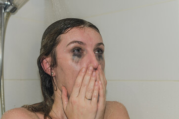 Young charming woman washes off mascara from her eyes in the shower	
