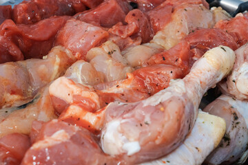 Raw pork skewers and chicken thighs cut into pieces and on skewers closeup