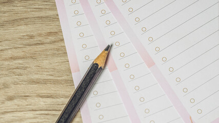 Close-up of pencil on empty white lined paper blanks. Wooden table background. Top view.