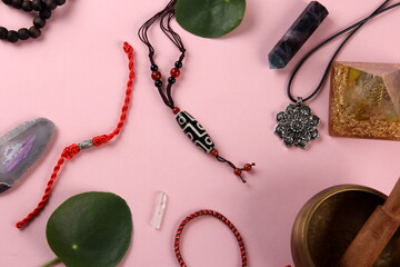 Tibetan dzi bead amulet necklace, tibetan singing bowl and other Success and prosperity symbols on a pink background
