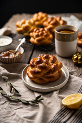 Breakfast with knot buns, orange jam, cream cheese and  black tea with lemon on wooden table. 