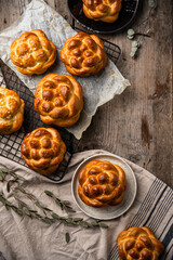 Homemade brioche knot buns on cooling rack on wooden table. 