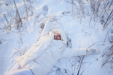 Happy elderly senior mature woman in white warm outwear playing with snow in sunny winter outdoors. Retired healthy people holiday vacation winter activities, active lifestyle concept.