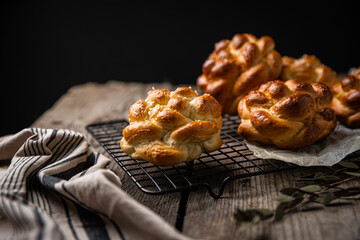 Homemade brioche knot buns on cooling rack on wooden table. 