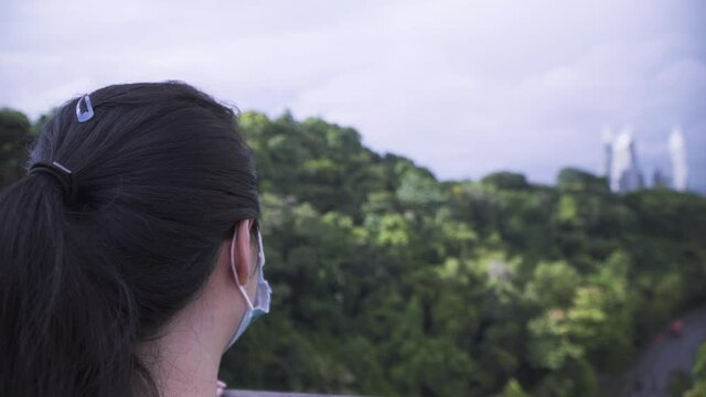 Woman Wearing Facemask Admiring The Scenic Nature View From Henderson Waves Pedestrian Bridge In Singapore During Pandemic. - rear, close up
