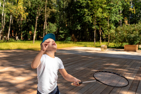 emotional boy in white t-shirt plays bambinton on a summer day