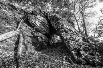 Schwarz weiß Bild Alte verwitterte Granit Felsen Formation mit Höhle und Durchbruch im Wald auf...