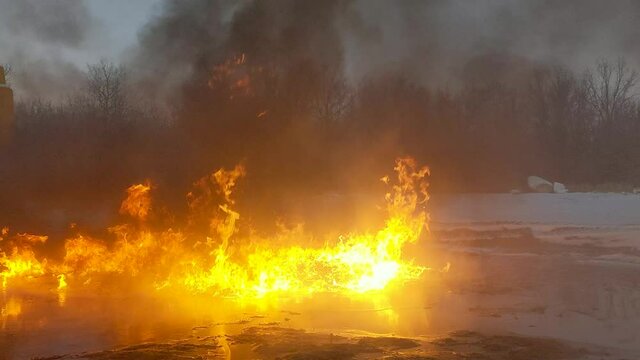 Burning oil spill created fire whirls, fire tornados or fire devils. Melted snow around the spill creates a reflective pool that the fire is burning on top of.