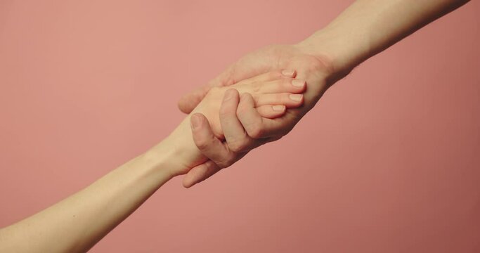 helping hand - support, assistance and charity concept. hands reaching together on pink background