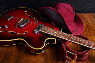 Jazz guitar, cowboy hat and belt on a wooden background.