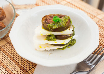 caprese salad with mozzarella, black tomatoes and pesto in white plate