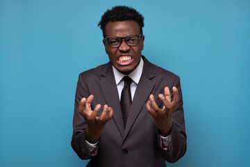 African man in suit being furious and angry clenching fingers. Negative facial human emotion.