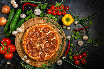Tasty pepperoni pizza and cooking ingredients tomatoes basil on black concrete background. Top view of hot pepperoni pizza. With copy space for text. Flat lay. Banner