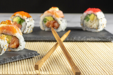 Japanese cuisine. Sushi placed on a black plate accompanied by sauce and chopsticks. Selective focus