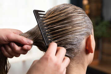 Hairdresser doing treatment after applying hair coloring , hair dye for a blonde women at home or salon.