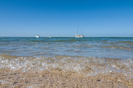 close up image of waves breaking on the beach at La Paz Bay,  with boats at the bottom. Sea of Cortes Baja california sur. MEXICO