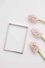 Wedding or birthday flat lay composition with pink flowers and blank photo frame, mockup, invitations. top view, copy space. 