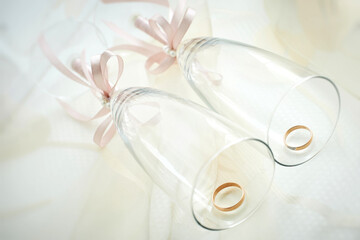 gold wedding rings on a in glasses decorated with pink ribbons. preparing for the wedding. close-up, macro