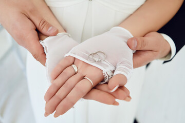 silver wedding rings on the palms of the bride. the groom holds the bride's hands.
