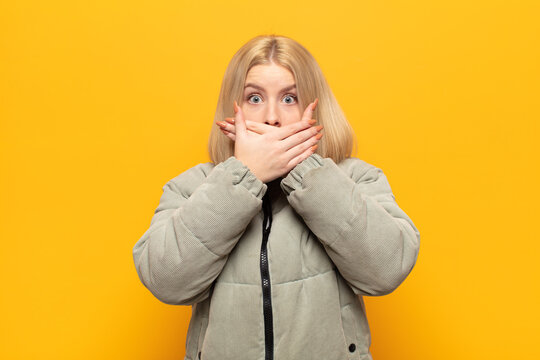 blonde woman covering mouth with hands with a shocked, surprised expression, keeping a secret or saying oops