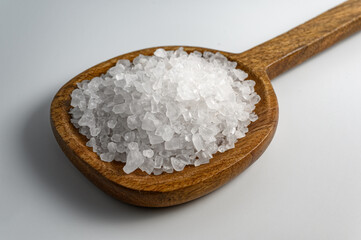 Sea salt in wooden spoon on white background