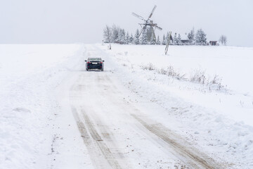 The car is going to the windmill in snowy day