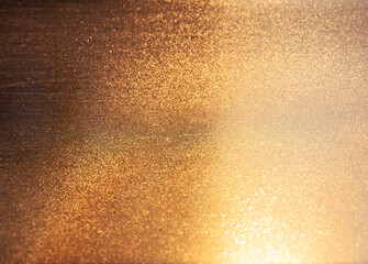 Abstract golden background with many small sparkles. Gradient from dark to light