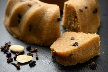 Homemade semolina halva with raisins served on black dish with nuts