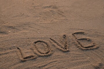 Handwritten love words on the beach sand