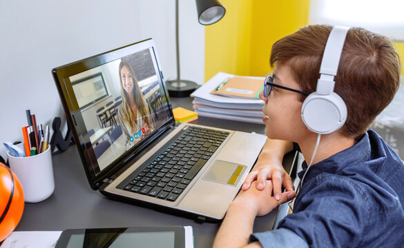 Boy with headphones receiving class at home with laptop from his bedroom. Home schooling concept