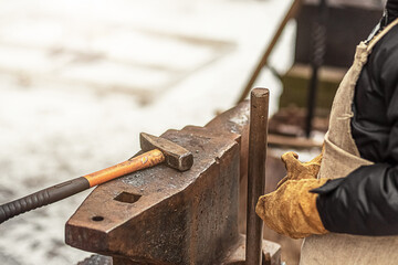 The boy, the blacksmith's son, stands at the anvil. The process of forging