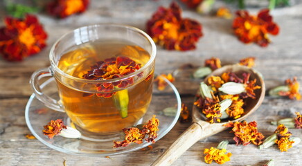Autumn healing background. Folk medicine Glass of herbal tea with marigold flowers on wooden ancient background with dried flowers Marigold tea benefits your health.