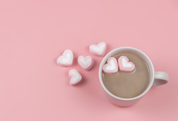 a cup of hot chocolate with  heart shape marshmallows on pink background with copy space. Valentine's day and beverage concept.