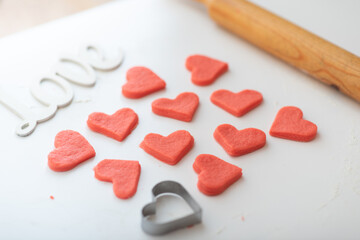 Fototapeta na wymiar Shortcrust pastry with red dye for making cookies for Valentine's Day in the form of red hearts.