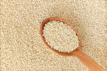 Sesame seeds in a wooden spoon, top view.