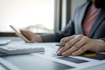 Fototapeta premium Businesswomen bookkeeper hand holding pen and use laptop doing account for paying tax on white desk in working office