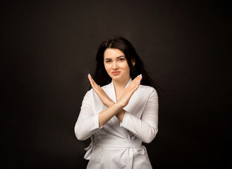 female doctor shows hands forbidding sign on black background with space for text