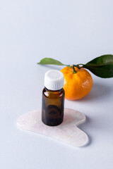 Ripe Tangerines and Small Bottle of Essential Citrus Oil Blue Background Spa Concept Vertical