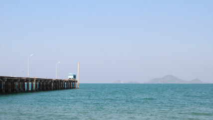 A bridge jutting into a bright blue sea with clear skies and blue houses.