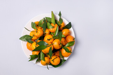 Fresh Ripe Tangerines on White Plate With Leaves Light Blue Background Top View Vertical