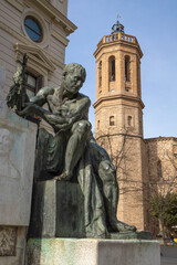 Joan Sallares and Pla monument (1917) by sculptor Josep Clara at Placa del Doctor Robert in Sabadell, Catalonia, Spain. Tower of the Church of Sant Felix on the background