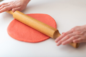 A woman makes homemade Valentine's Day cookies from shortcrust pastry in the form of red hearts.